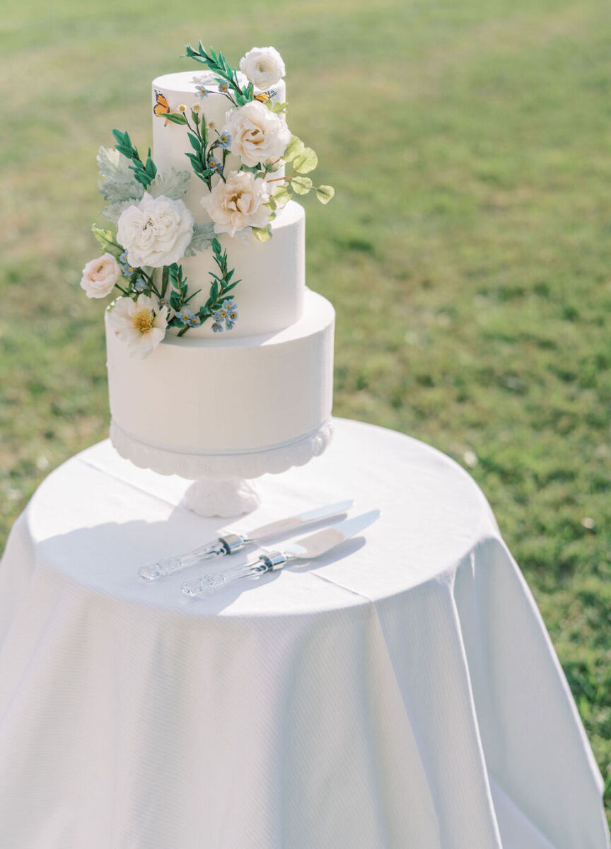 4th of July Wedding: A three-tiered white wedding cake on a table at an outdoor reception.
