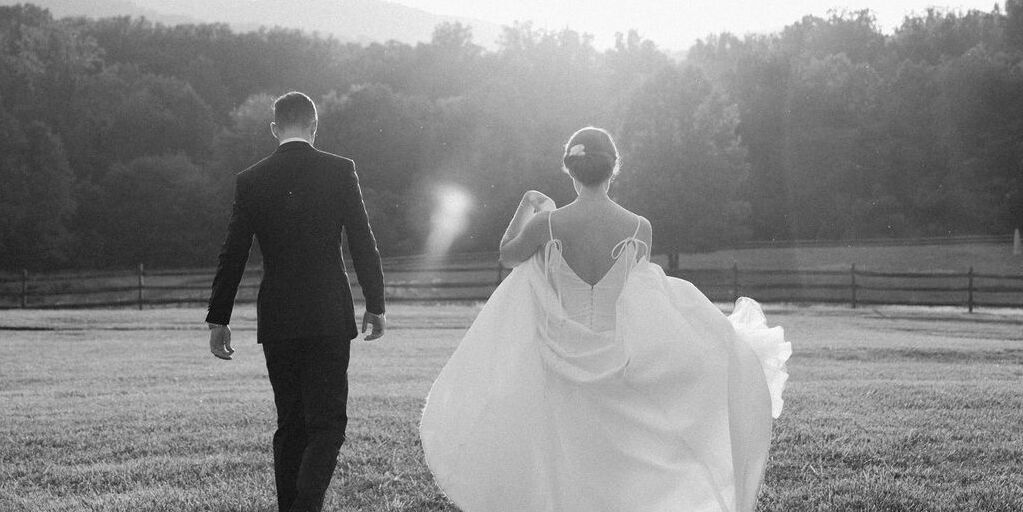 4th of July Wedding: A bride and groom walking away into the sunset towards the forested hills.