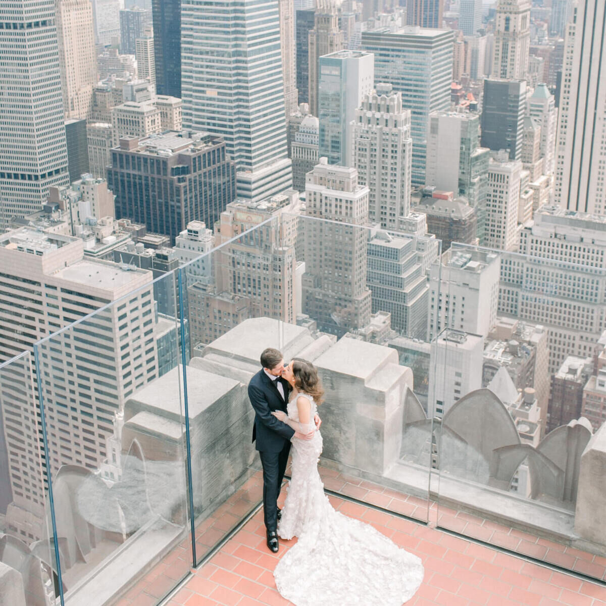 City Weddings: A couple posing on the rooftop at the Rainbow Room with New York City skyscrapers behind them.