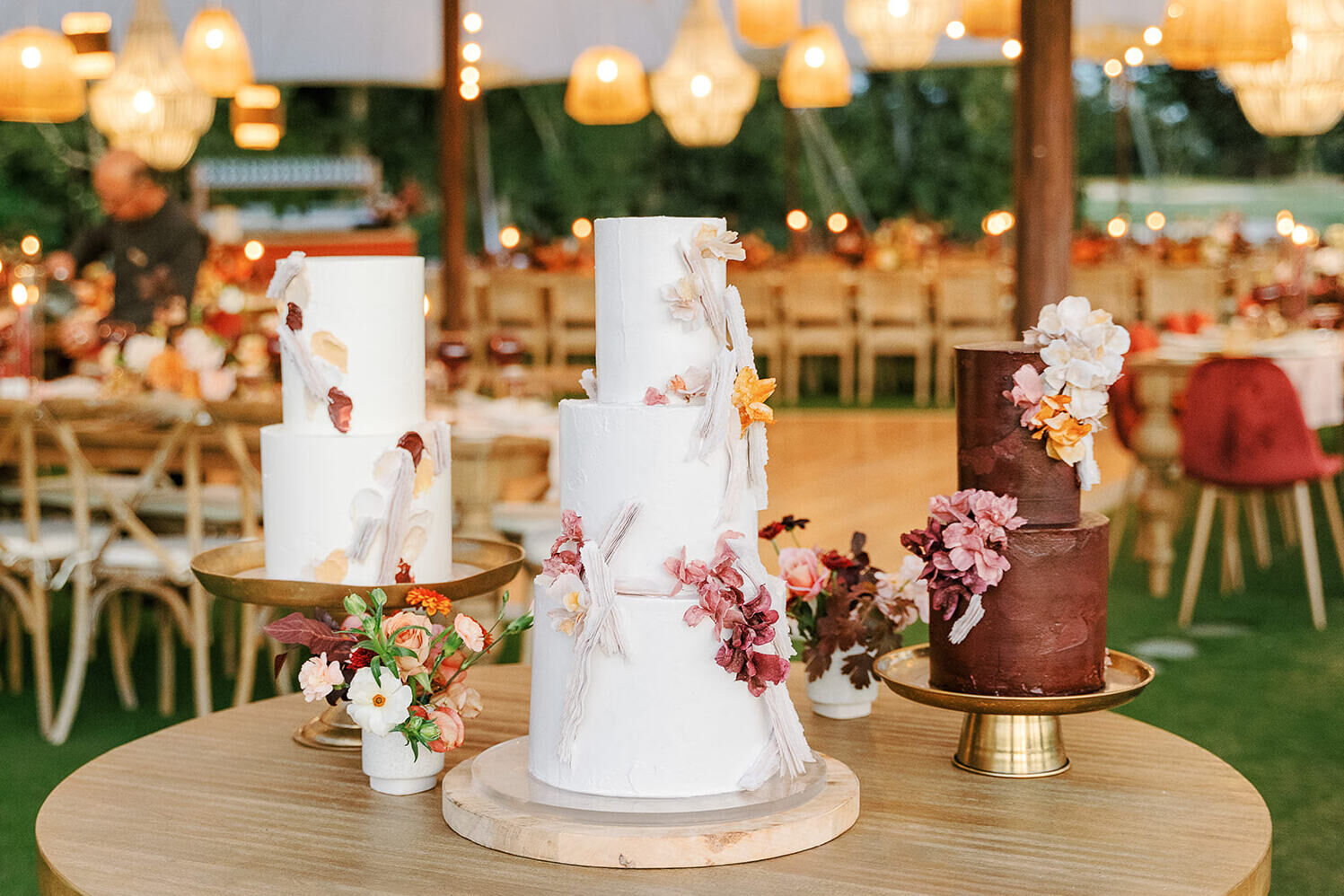 A trio of wedding cakes—two white and one a chocolate brown—boasting complementary decoration.
