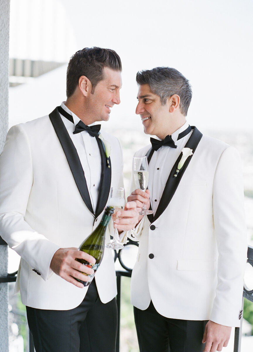 Wedding Traditions: Two grooms in white tuxes pouring glasses of champagne.
