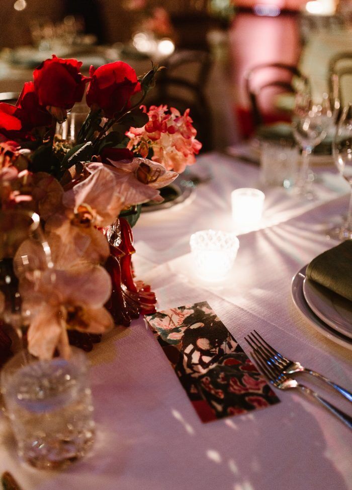 Wedding Traditions: Candles and red and pink floral arrangements on a reception table.