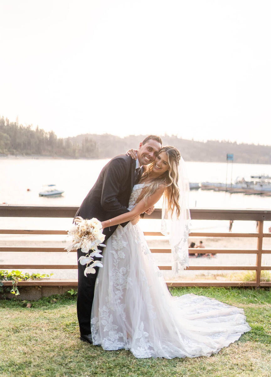 Adventurous Wedding Venues: A bride and groom arm in arm in front of a lake at The Pines Resort.