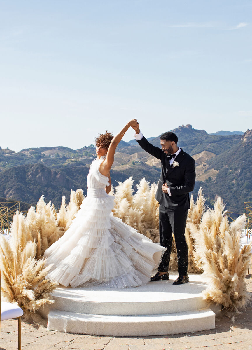 Adventurous Wedding Couples: A groom spinning a bride at a ceremony setup at Malibu Rocky Oaks Estate Vineyard.