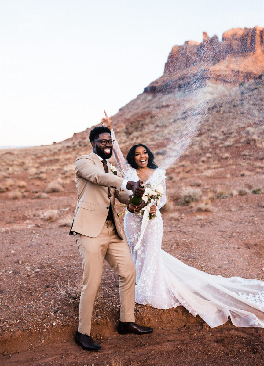 Adventurous Wedding Venues: A bride and groom smiling and popping champagne at The Red Earth Venue.