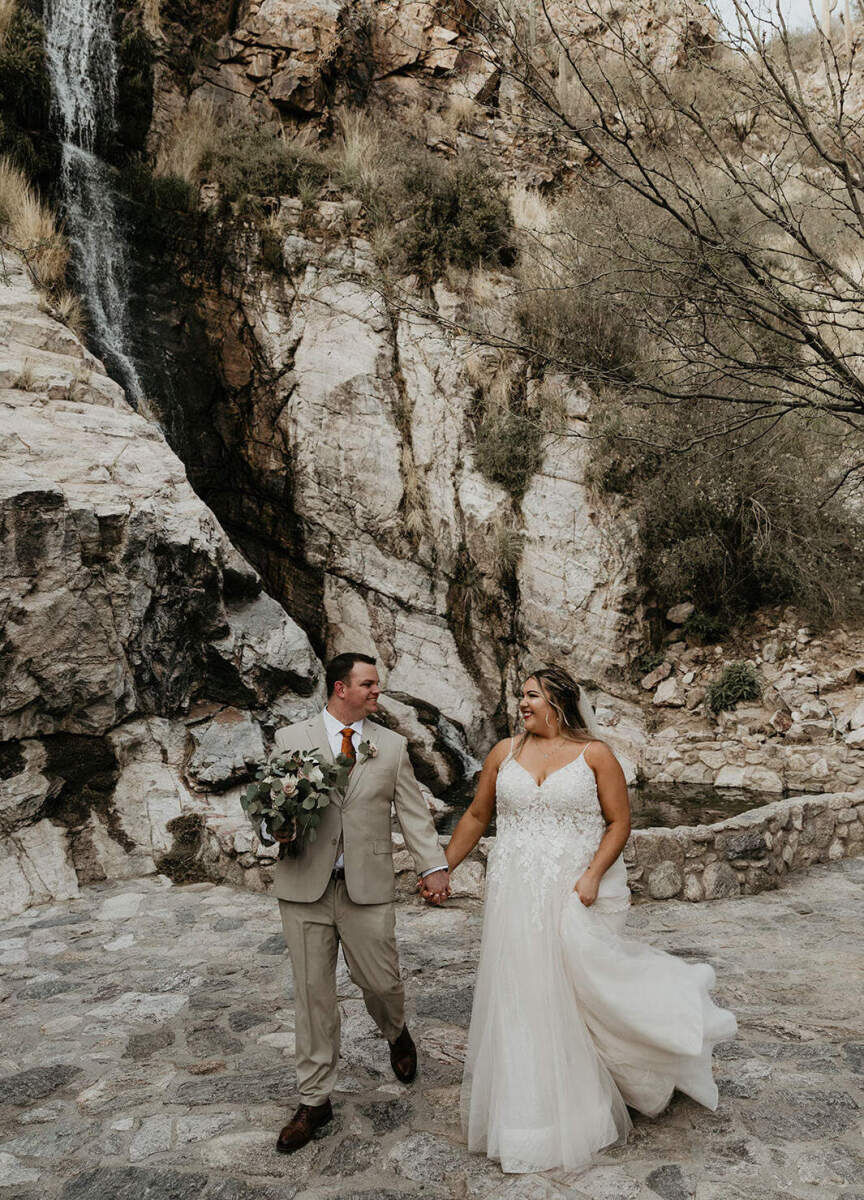 Adventurous Wedding Venues: A bride and groom holding hands and smiling at one another during their wedding celebration at Loews Ventana Canyon.