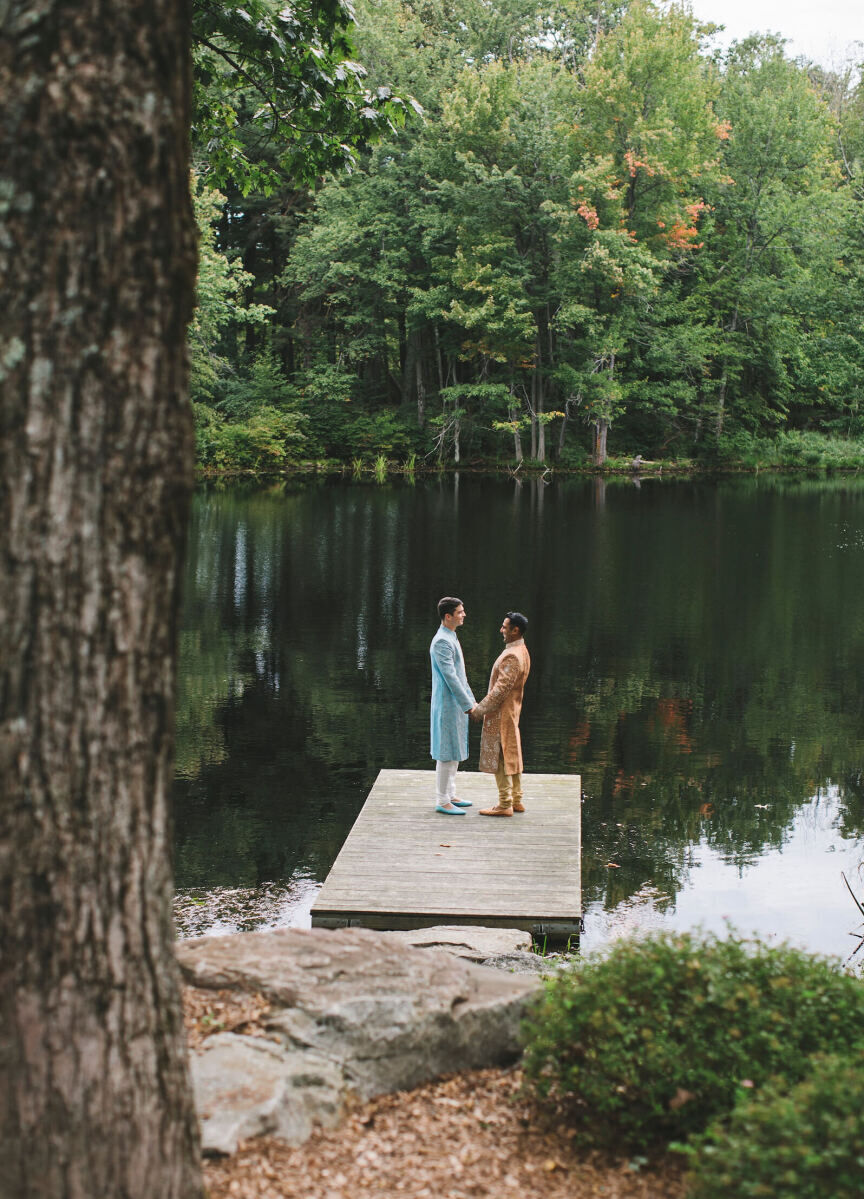 Adventurous Wedding Venues: Two grooms holding hands on a dock at Cedar Lakes Estate.