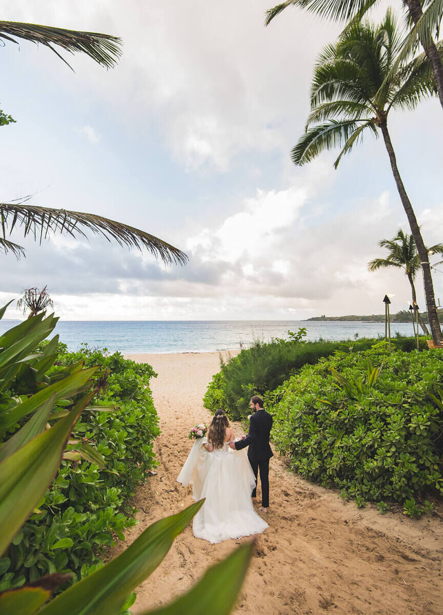 Adventurous Wedding Venues: A bride and groom walking on the beach during their wedding celebration at The Ritz-Carlton Maui, Kapalua.