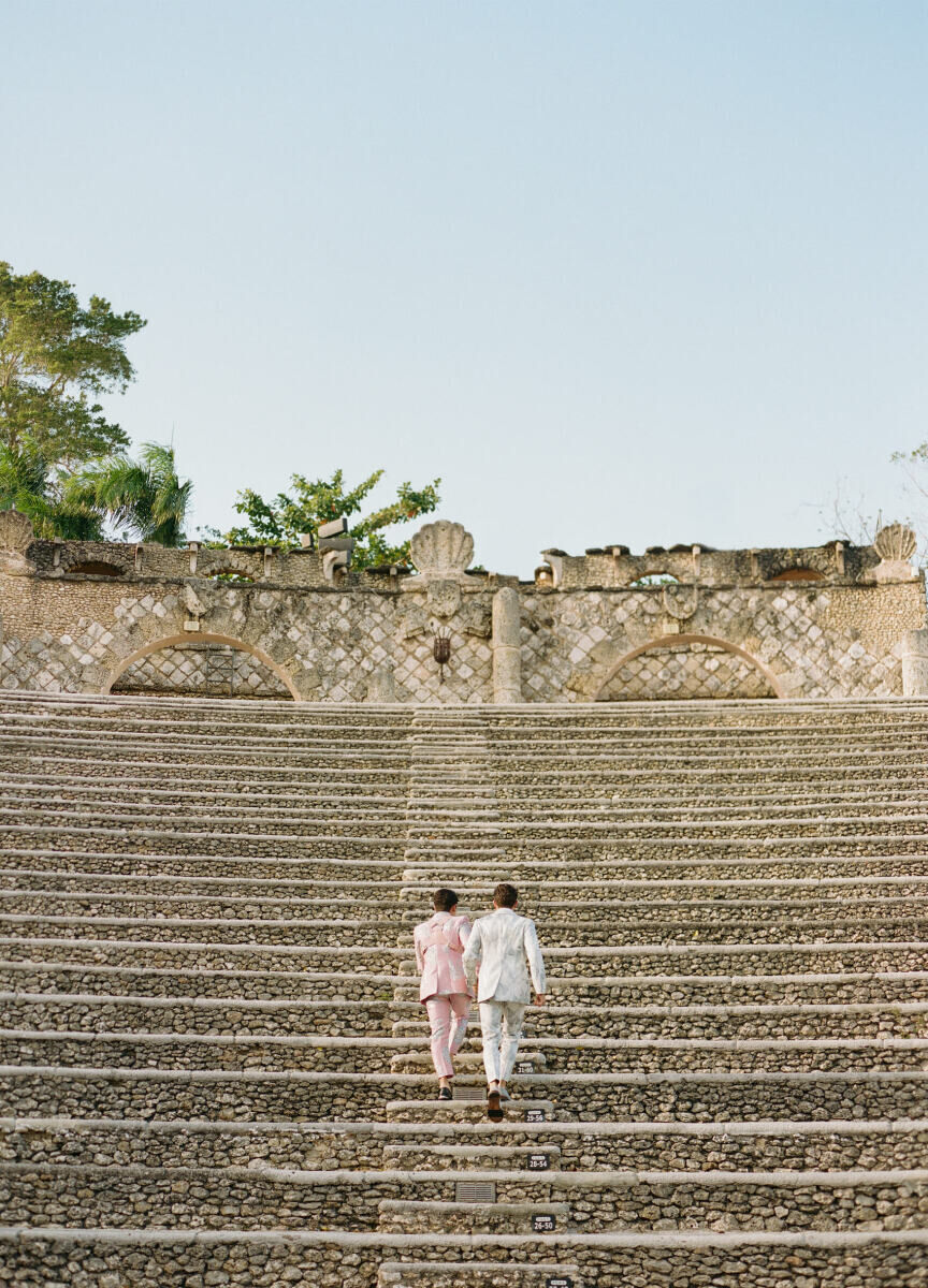 Adventurous Wedding Venues: Two grooms climbing beautiful rocky steps hand in hand at Casa de Campo Resort & Villas.