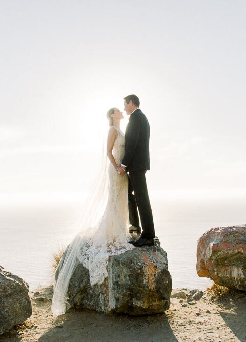 Adventurous Wedding Venues: A bride and groom standing on a rock on a cliff.