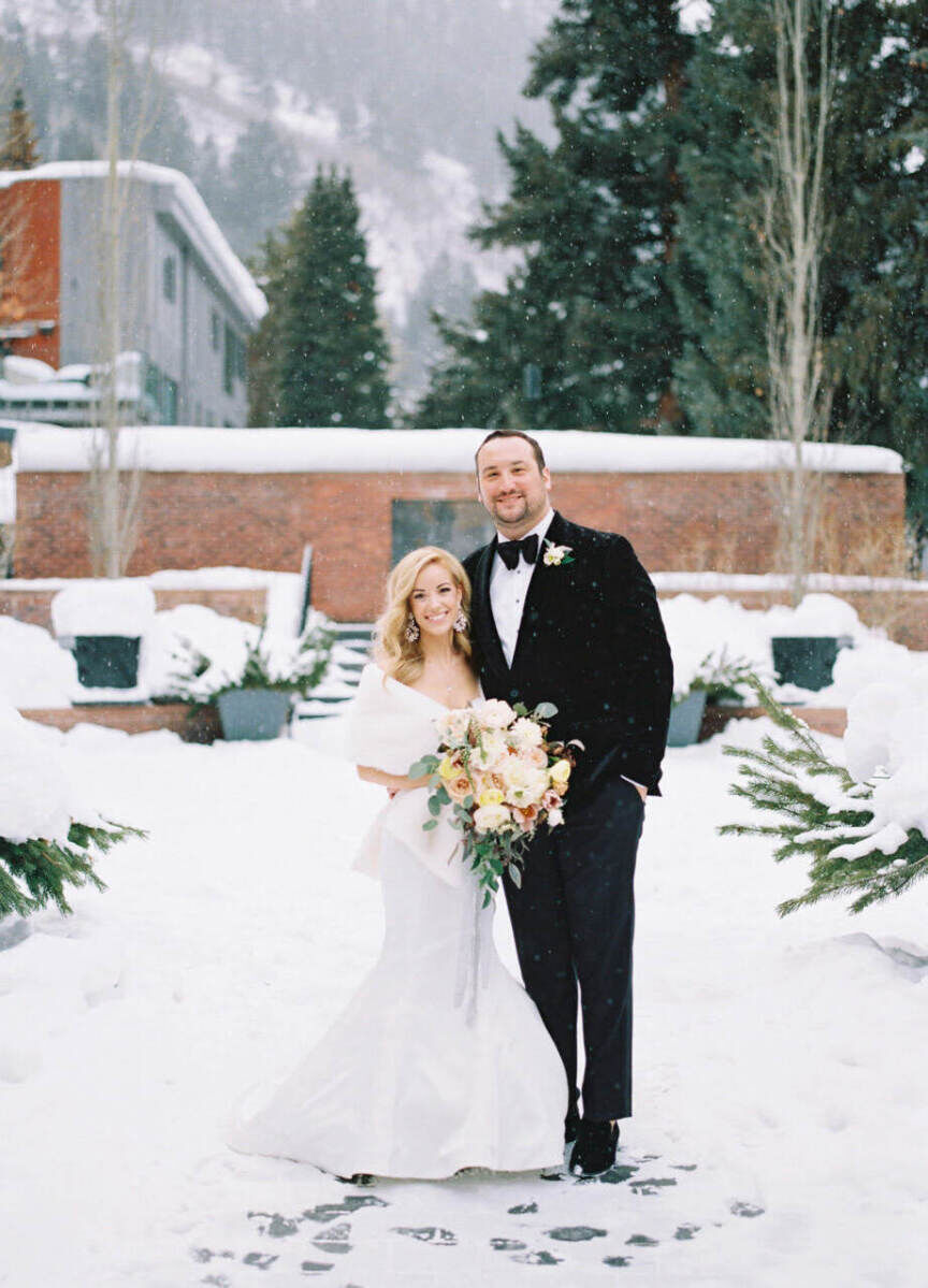 Adventurous Wedding Venues: A bride and groom posing and smiling outdoors in the snow at The St. Regis Aspen Resort.