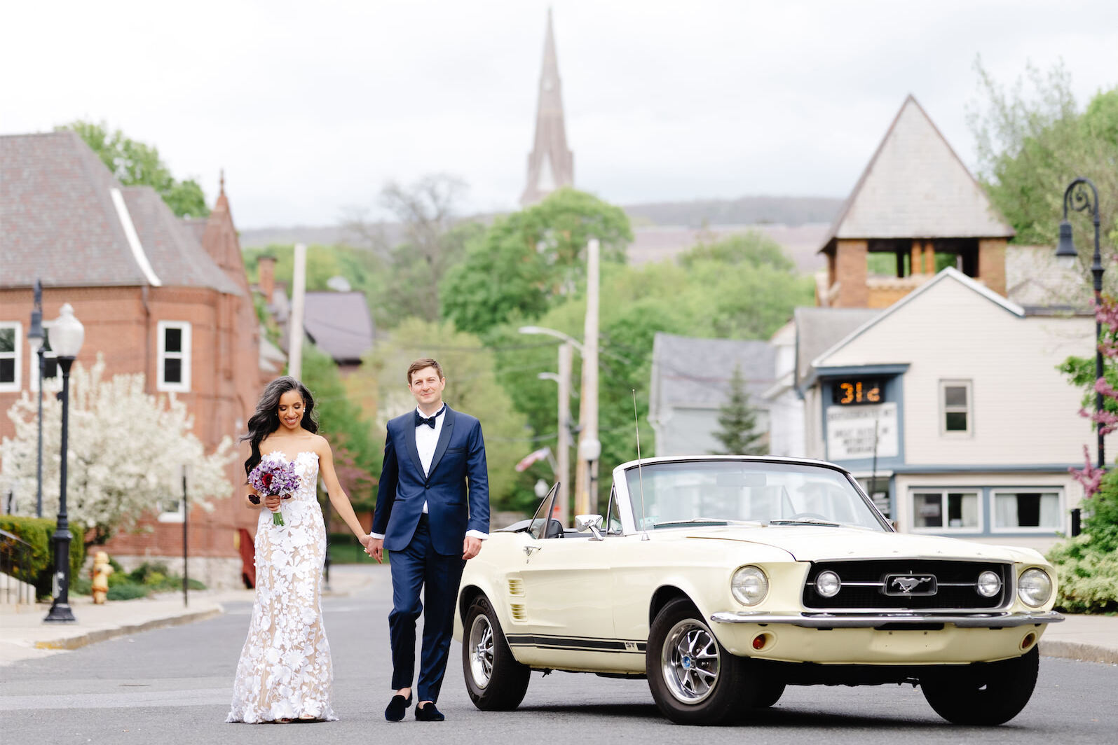A bride and groom pose by a rented vintage car that they used to get to their art museum wedding.