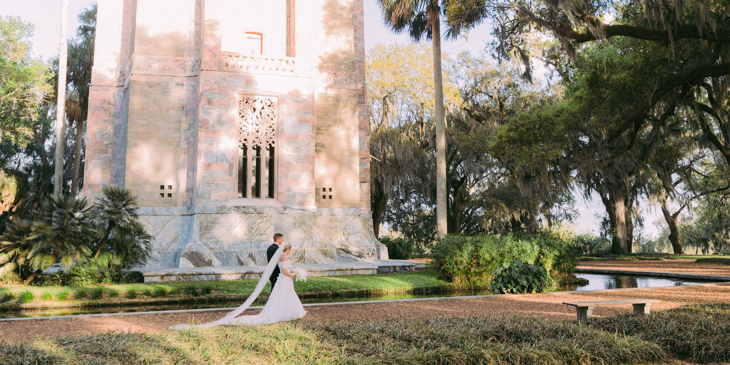 A bride and groom walk by their ceremony venue, Bok Tower Gardens.