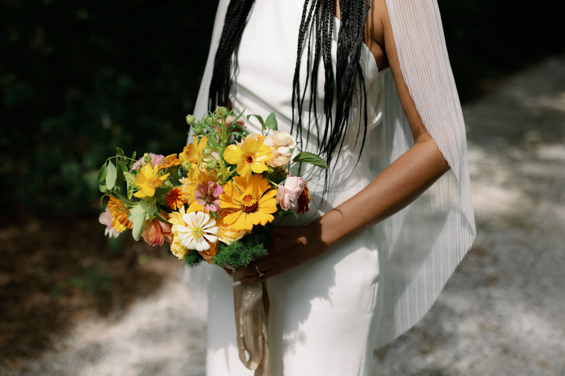 A bride holds a yellow and pink bouquet at her authentic modern wedding.