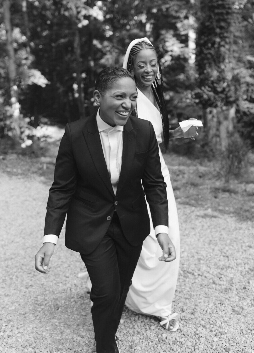 A pair of brides smile and walk the grounds of their Atlanta wedding venue during their authentic modern wedding.