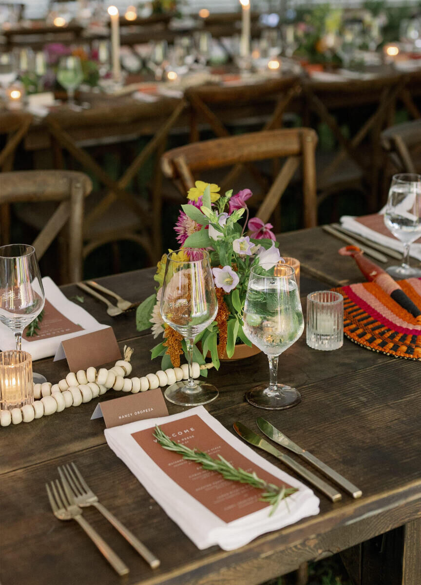 An authentic modern wedding reception incorporated fresh herbs, petite floral arrangements, and hand-woven fans on each of the wood tables.