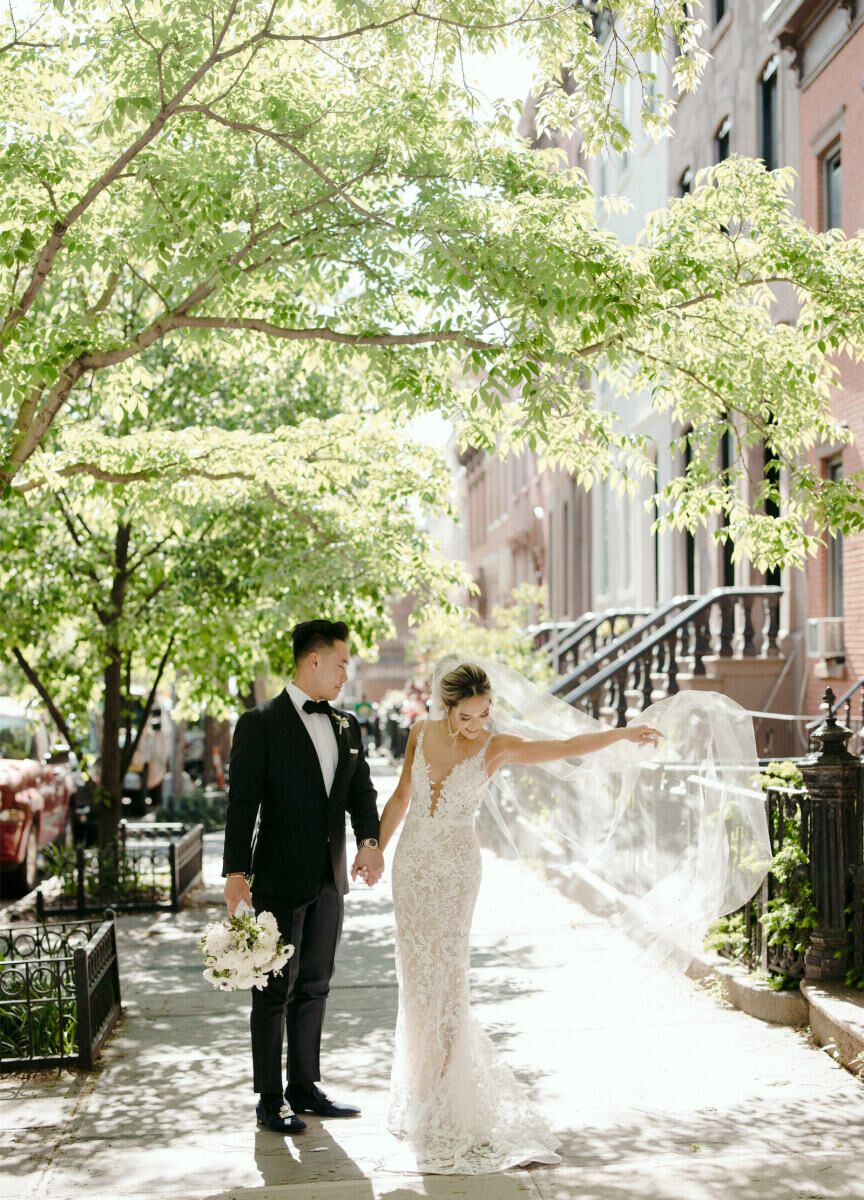 Average Wedding Dress Cost: White wedding dress with plunging neckline, lace detail, and long veil
