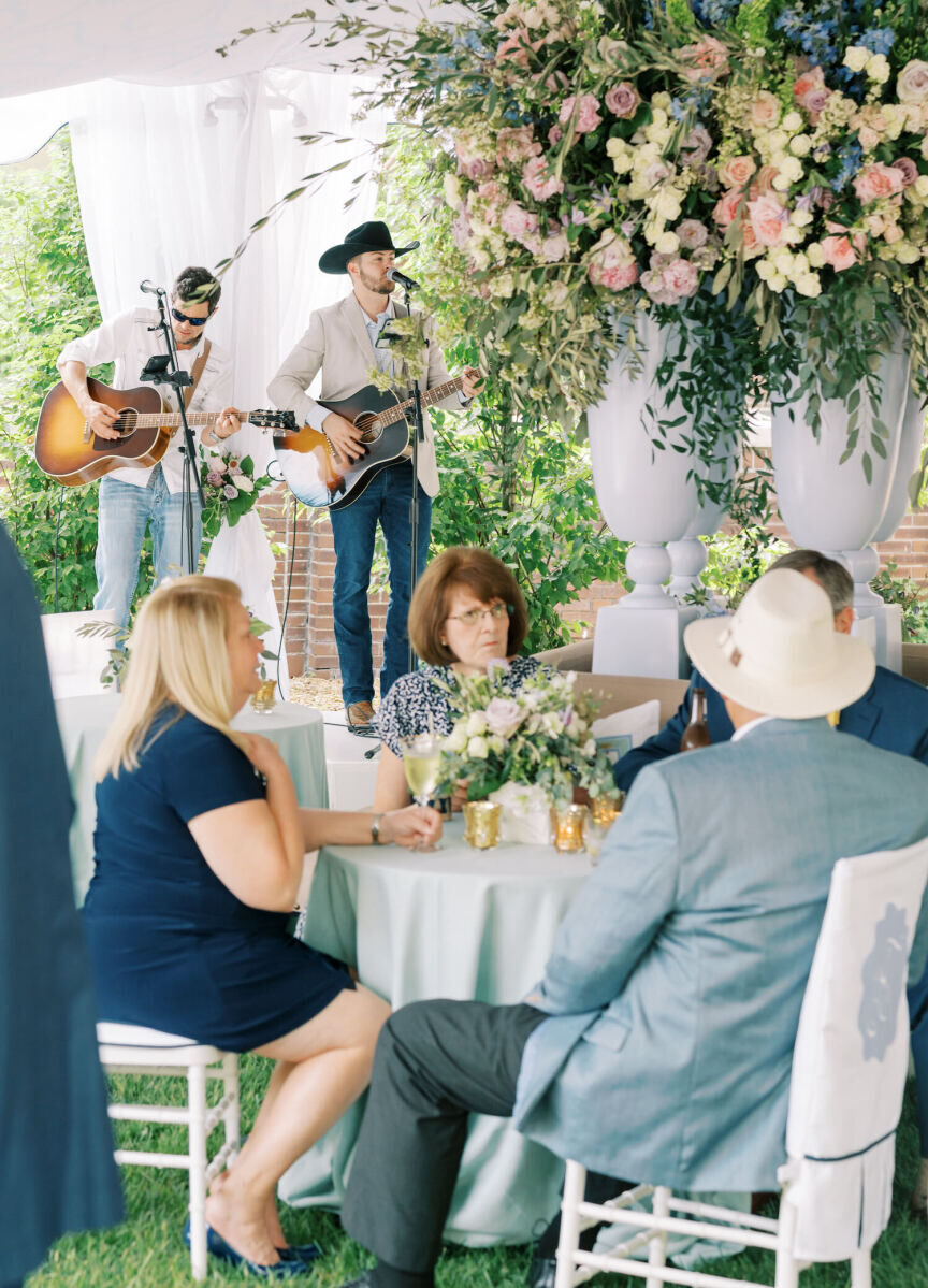 A backyard wedding reception, with live musicians playing inside the reception tent.