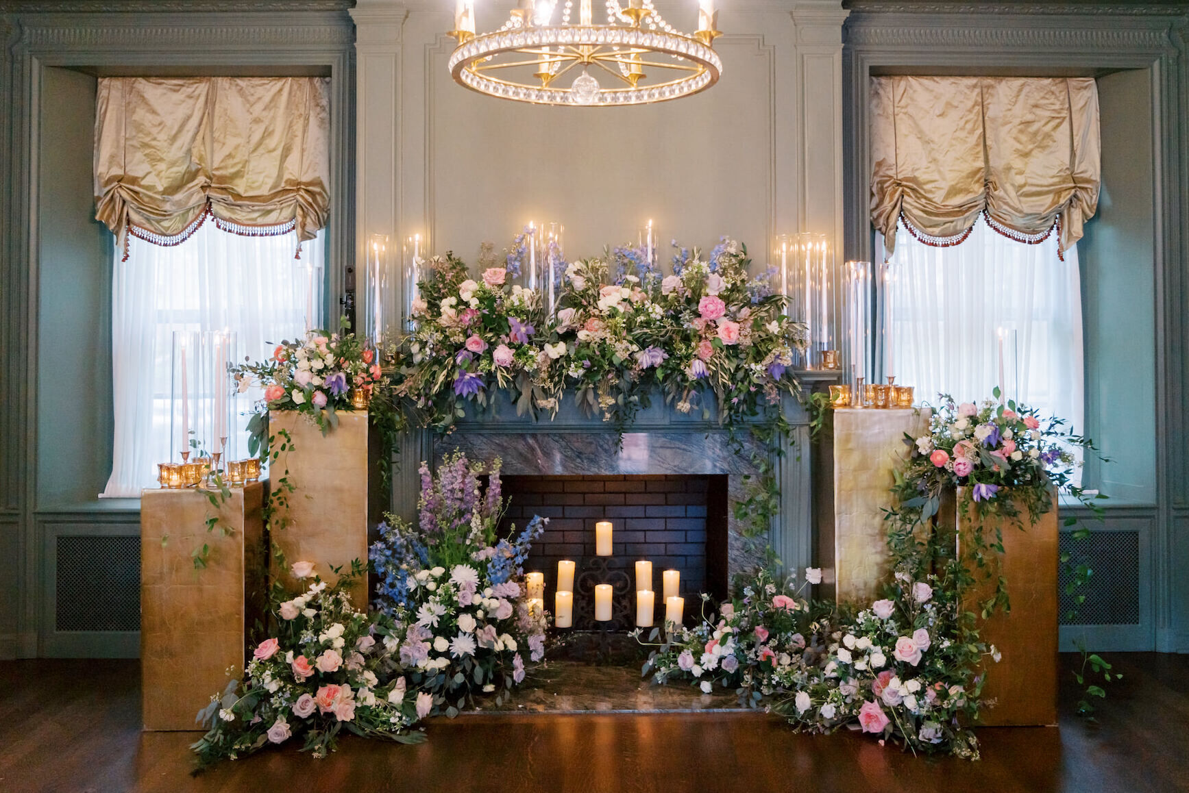 A fireplace decorated with pink and blue flowers for an at-home wedding ceremony.