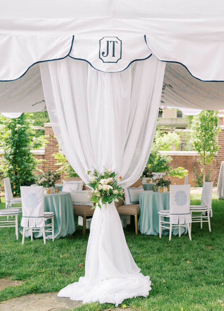 A tent at a backyard wedding features personal touches like the couple's monogram.