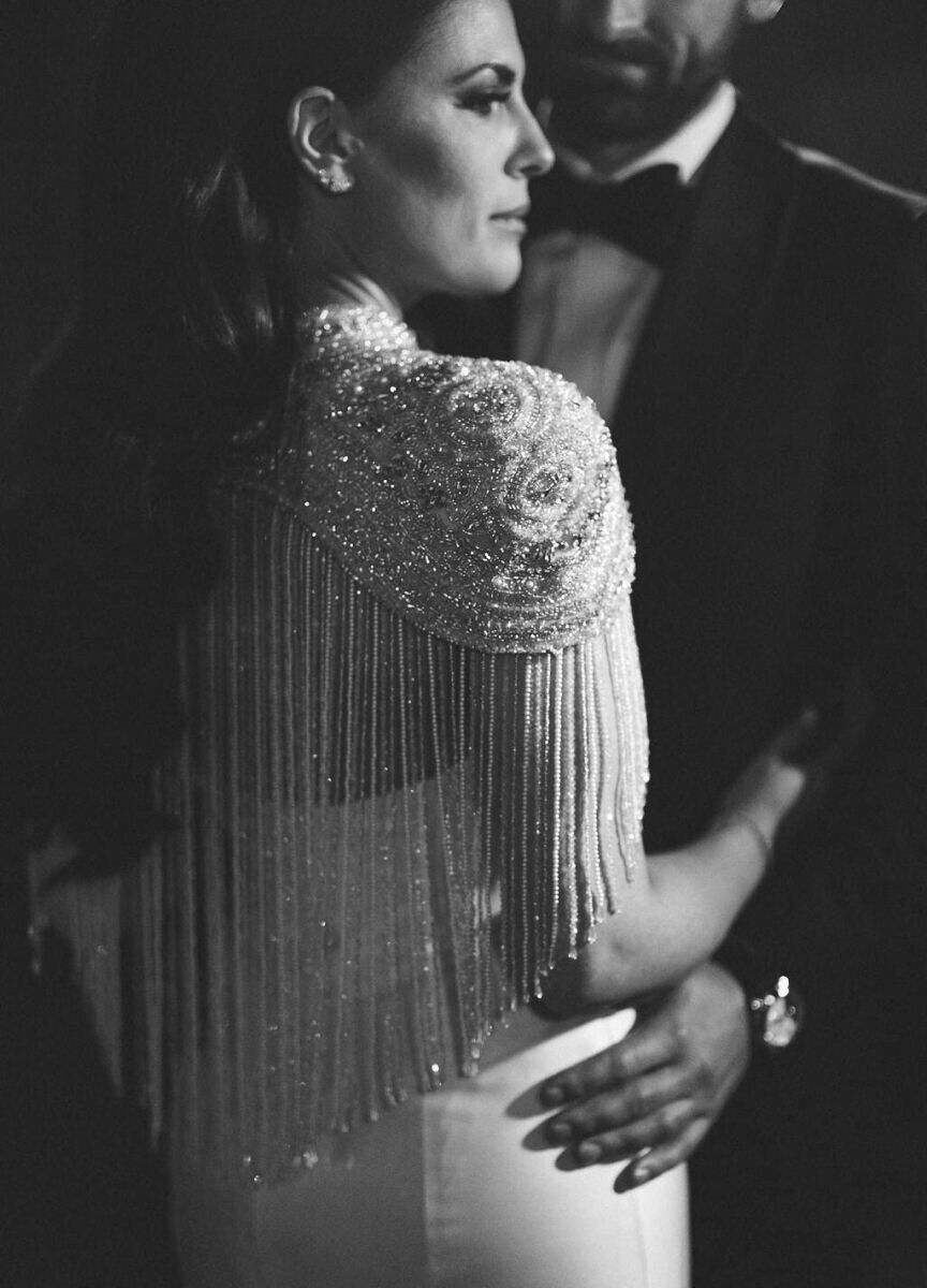 Ballroom wedding details: A bride's ornately beaded cap sleeve and cape detail over her wedding dress.