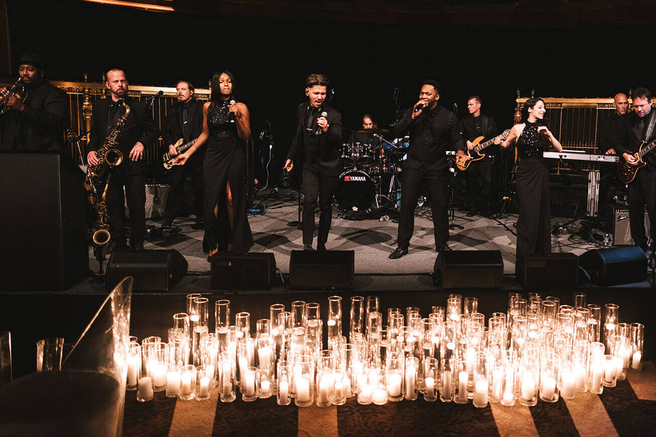 Ballroom wedding details: A band plays during a reception of a ballroom wedding, with candlelight surrounding the stage.