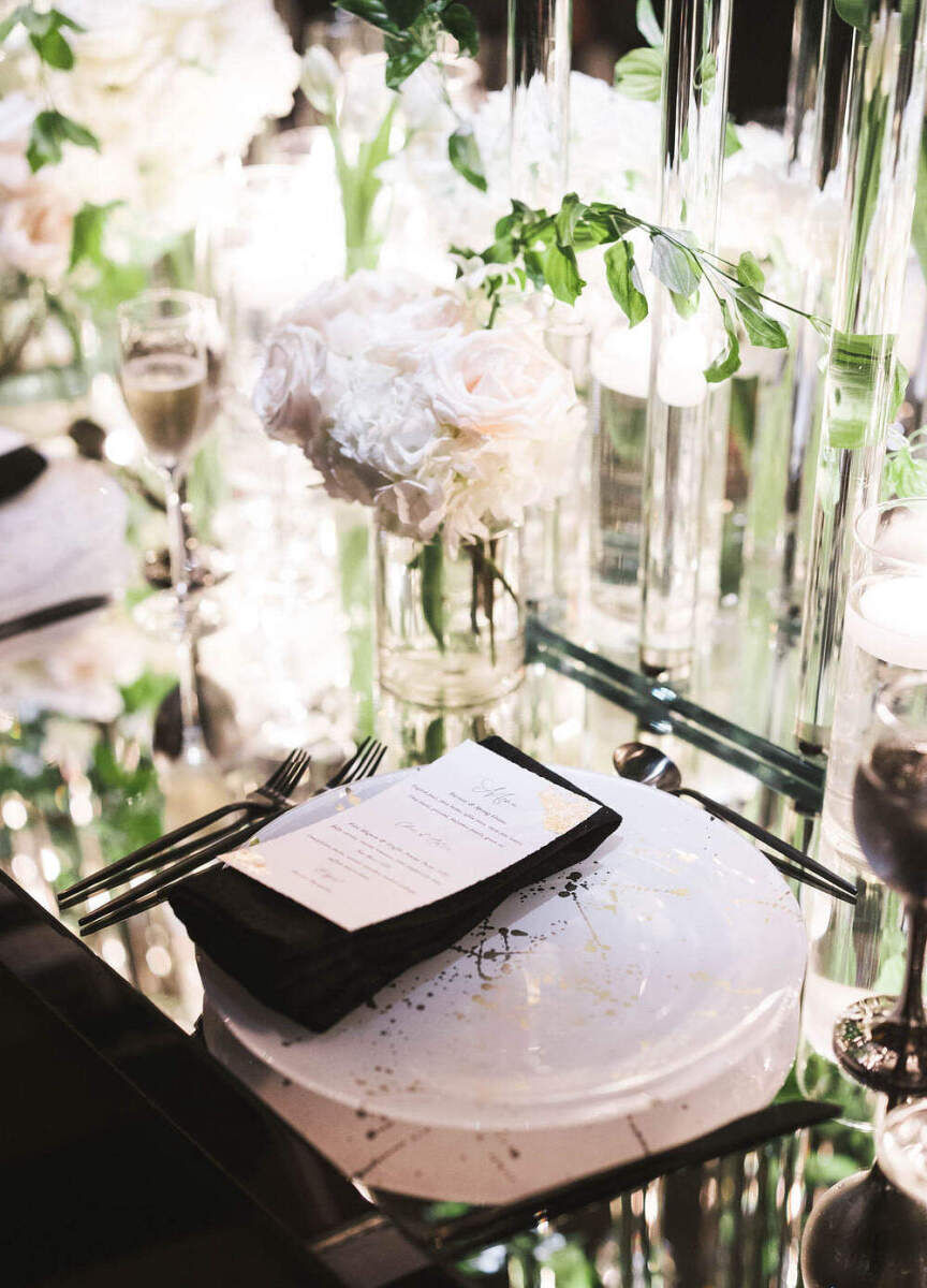 Ballroom wedding details: Gold splattered plates atop a mirrored reception table at a glam wedding.