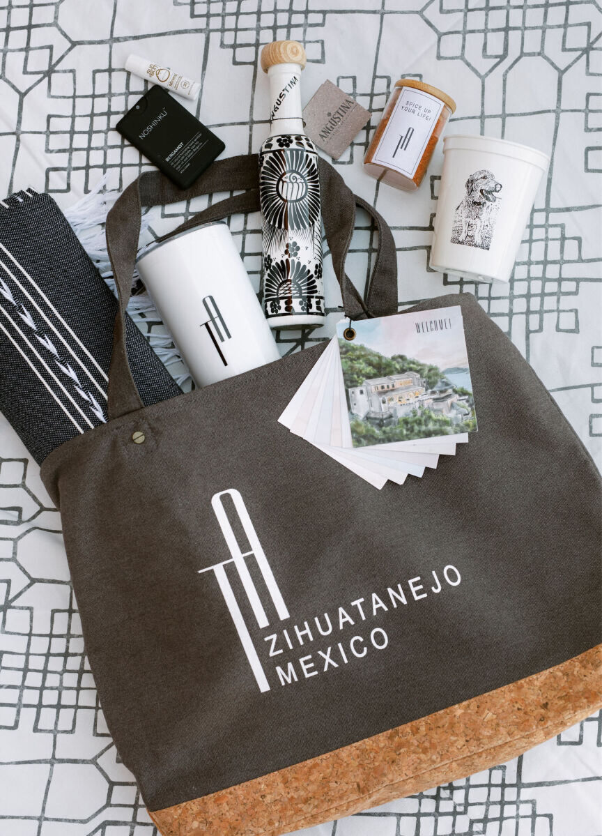 A wedding welcome bag filled with local amenities such as tequila and spices, as well as other items branded with the couple's monogram.