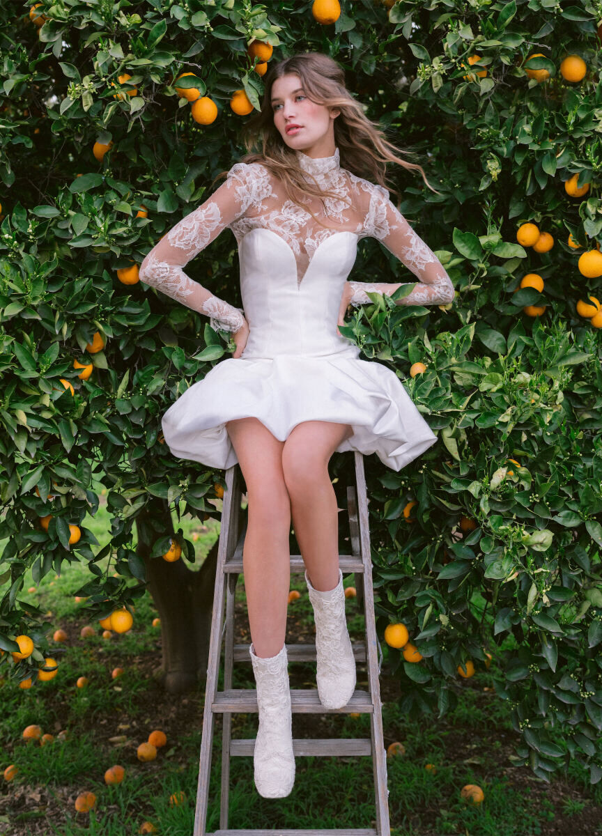 Bridal Fashion Week: A bride in a mini dress from Monique Lhuillier sitting on a step stool in front of an orange tree,