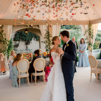 Wedding couple dancing underneath colorful  reception  installation