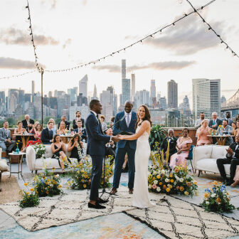 Wedding couple holding hands on rooftop ceremony