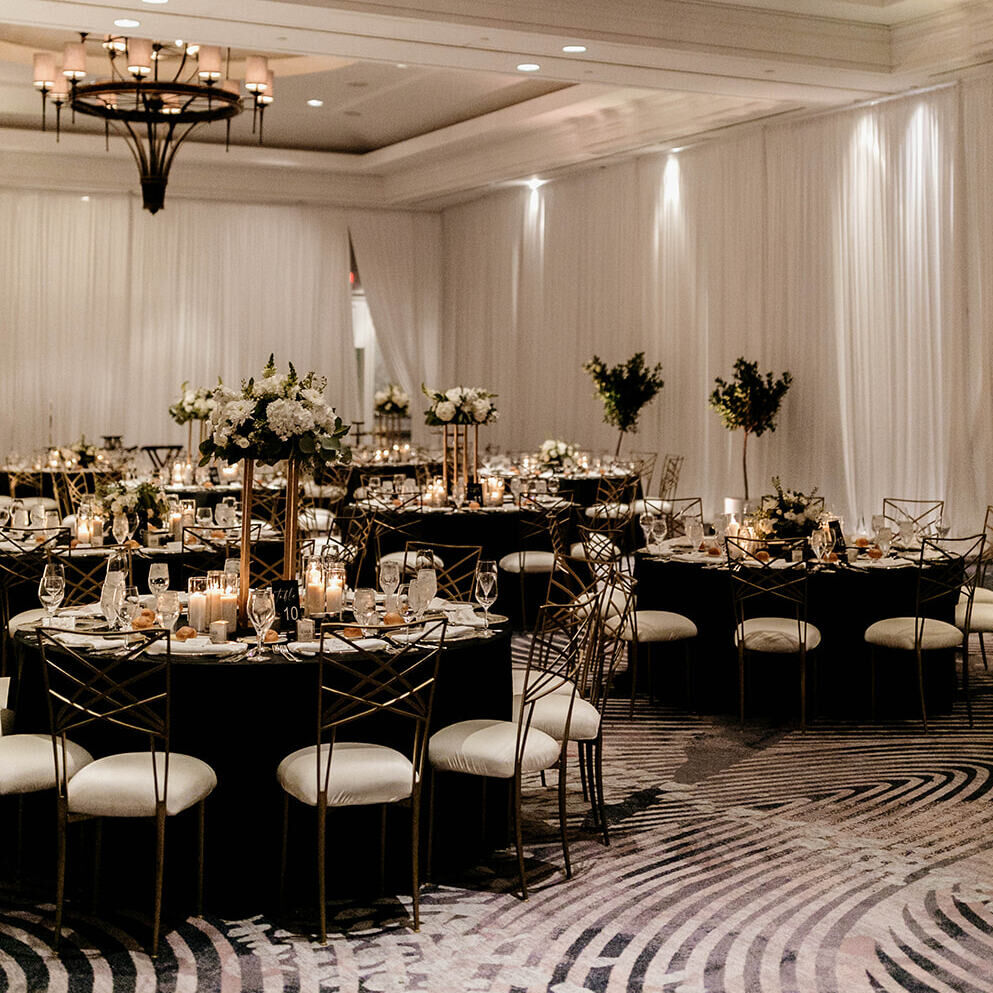 Black and cream glam wedding reception set up in the ballroom of the Loews Coronado Bay Resort 