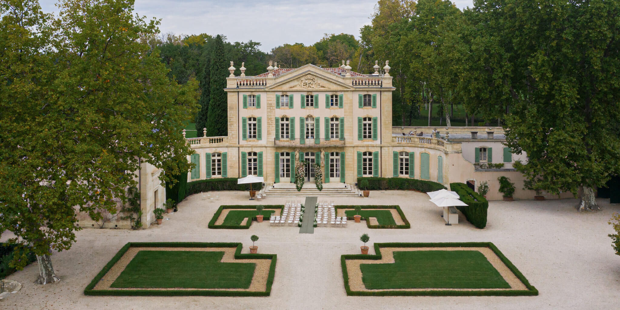 Castle Wedding Venues: A chateau in France surrounded by trees with manicured lawns and green-shuttered windows.