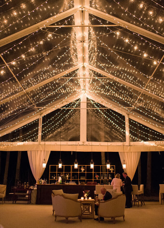 Wedding Ceiling Decor: String lights hanging from the ceiling of a see-through outdoor wedding tent.