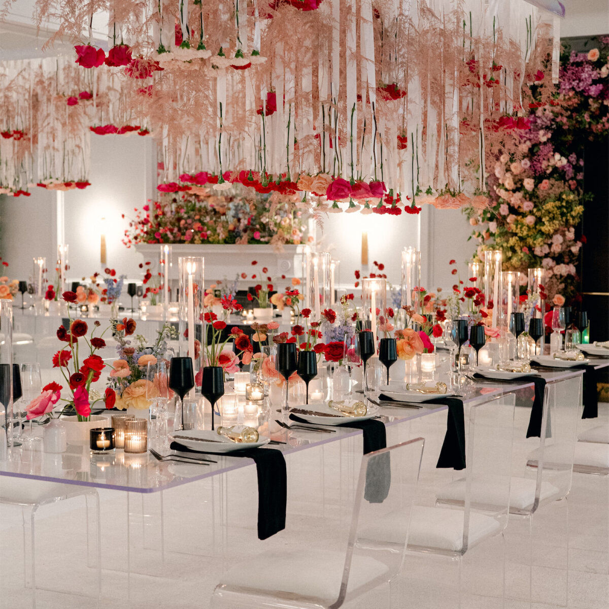 Ceiling Wedding Decor: Roses hanging upside down at a rainbow-colored reception space with long glass tables and acrylic chairs.