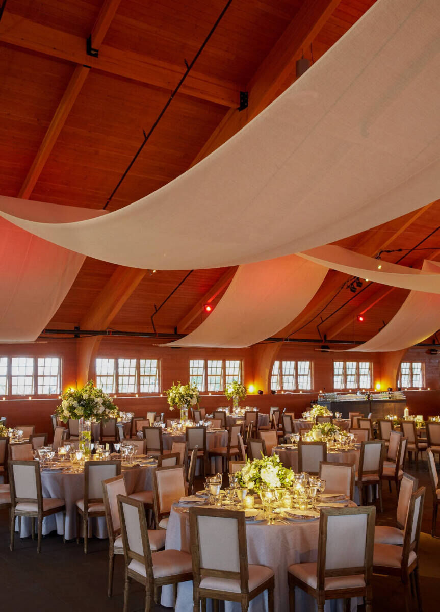 Ceiling Wedding Decor: Fabric drapery hanging from the rafters at a wedding venue with stables.