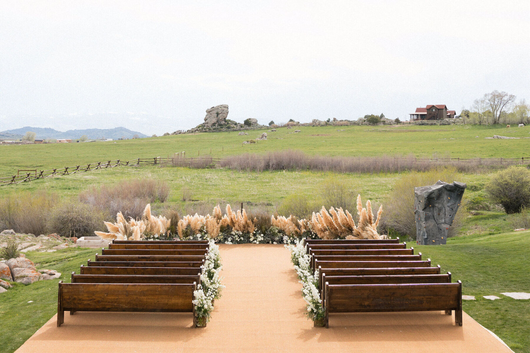 Celebrity Wedding: An outdoor ceremony setup with wooden benches overlooking a grassy area at a ranch in Wyoming.
