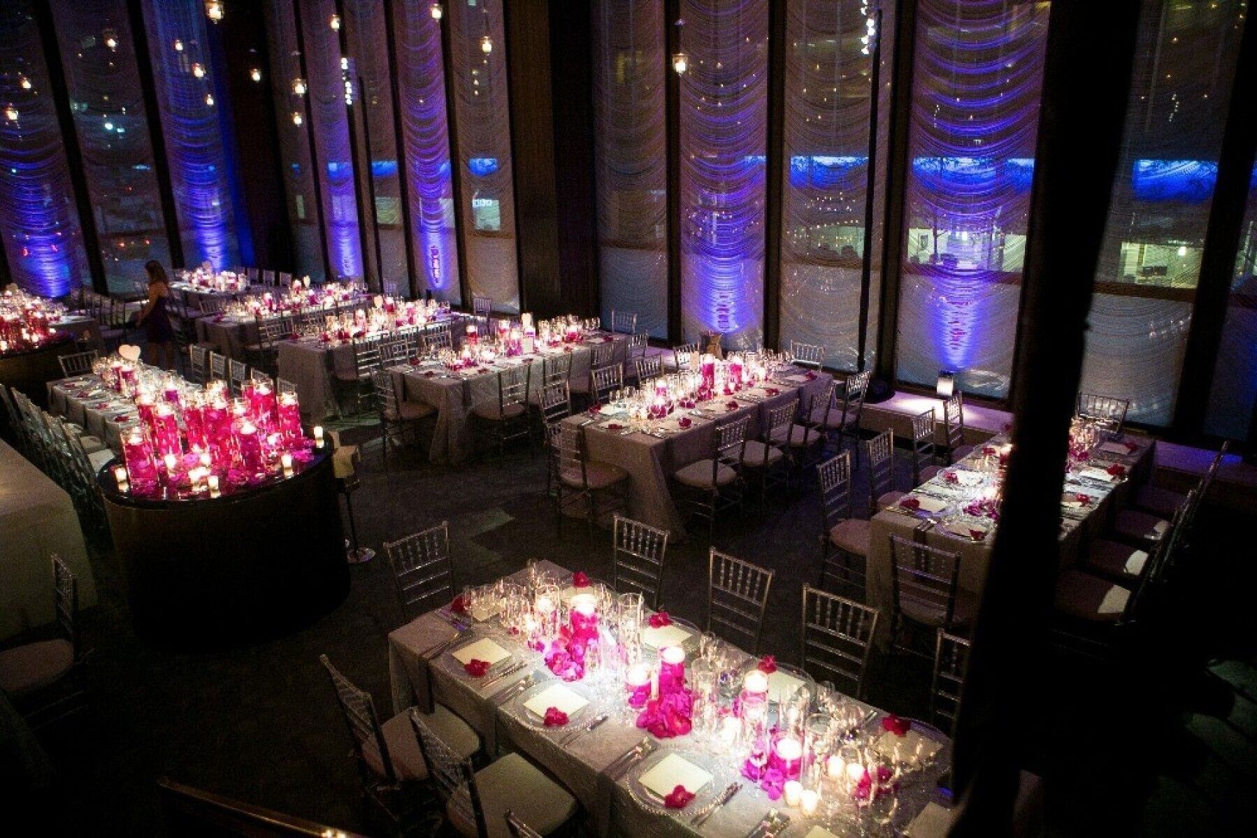 Celebrity Wedding: An indoor reception setup with rectangular tables in a dimly-lit room.