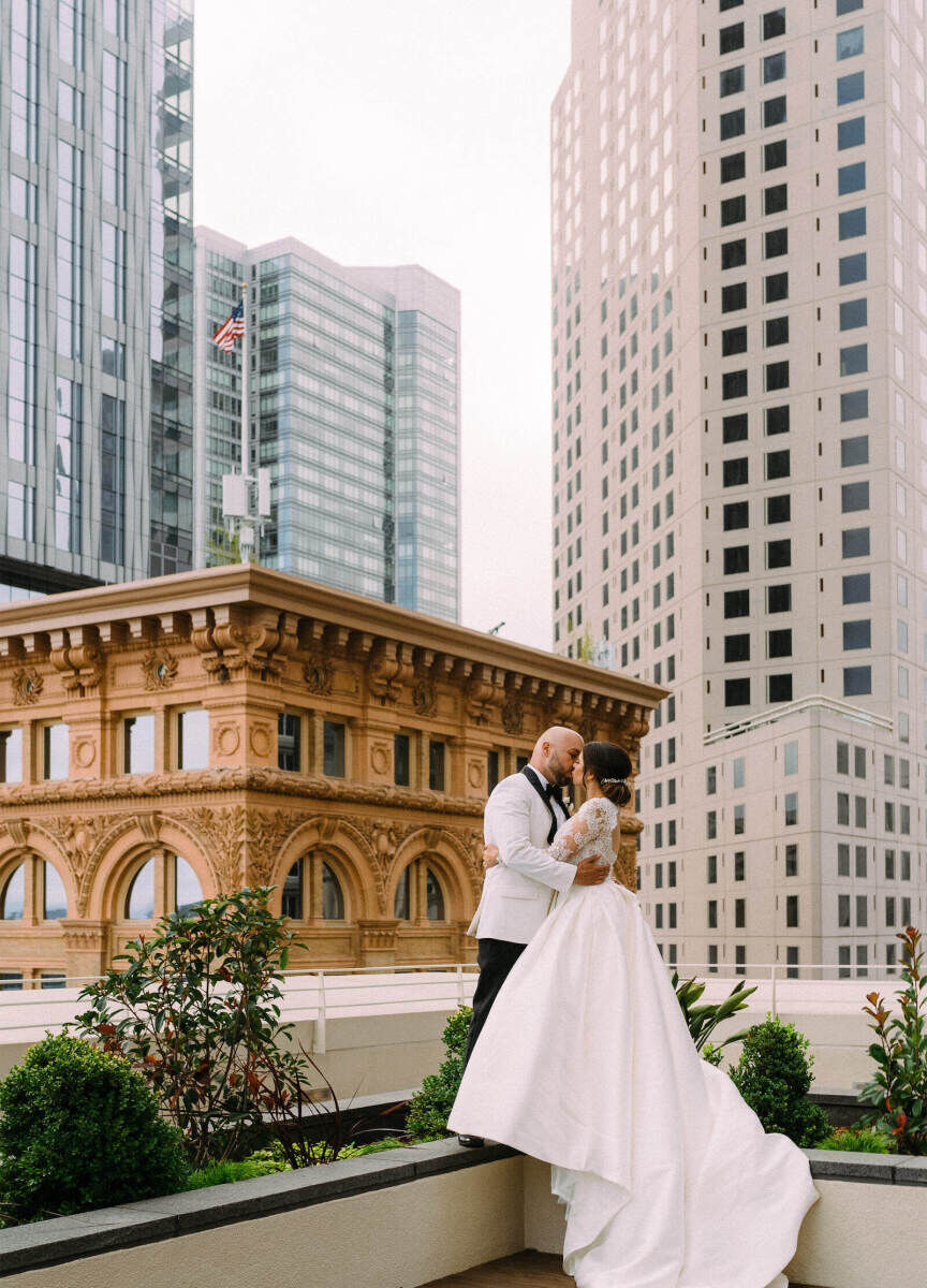 City Weddings: A wedding couple kissing on a rooftop overlooking San Francisco, California.