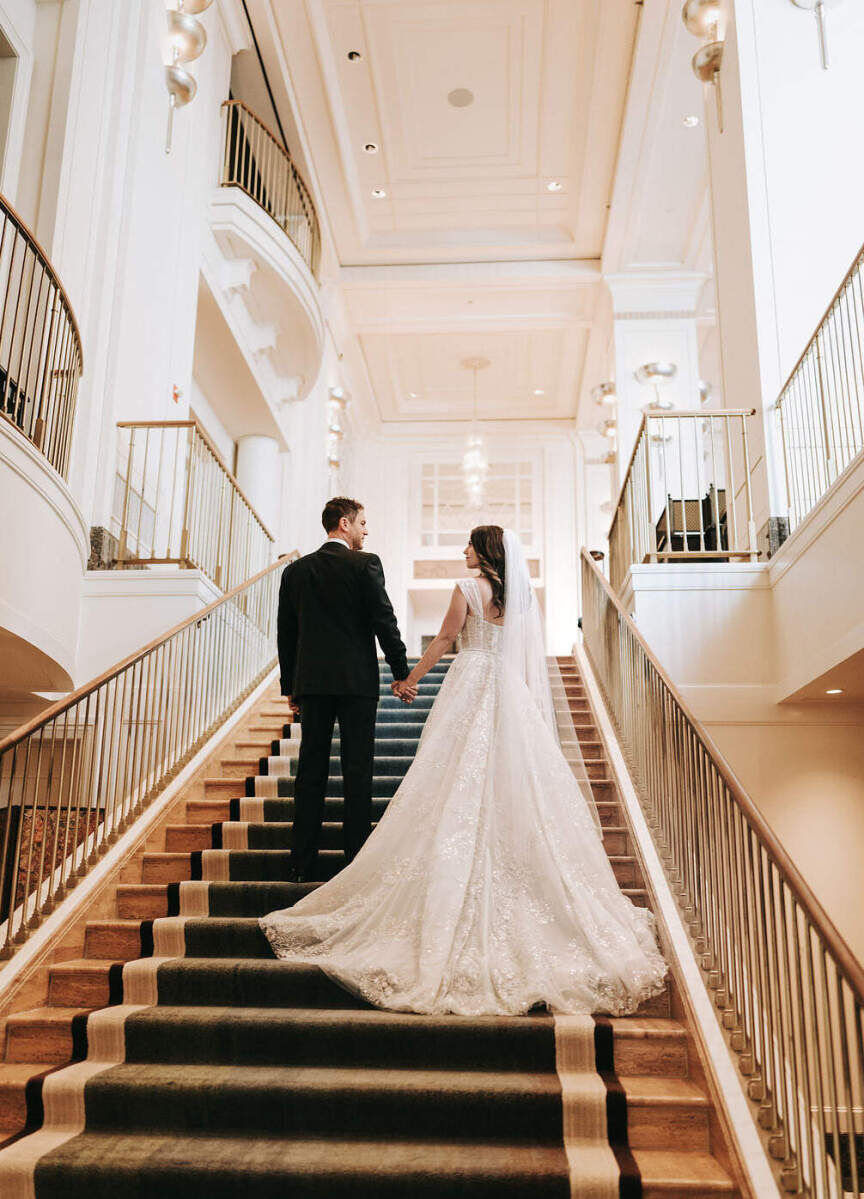 City Weddings: A wedding couple holding hands on a staircase at The Peninsula Hotel in Chicago.