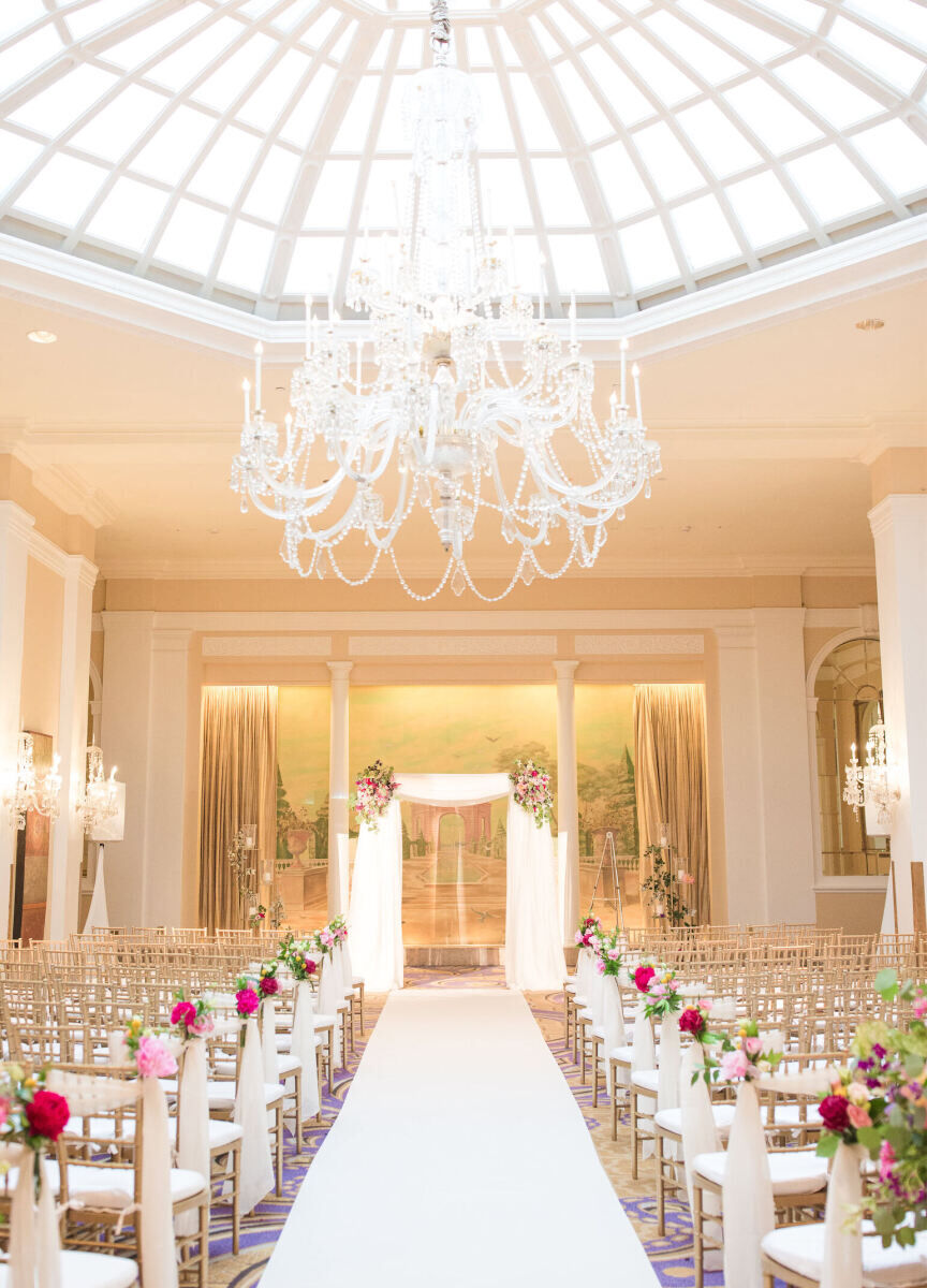 City Weddings: An indoor wedding ceremony with a rounded glass ceiling and chandelier above.