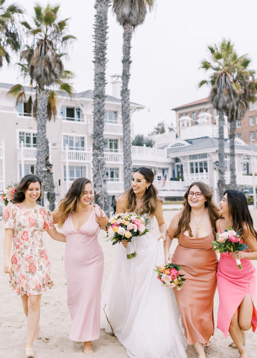 City Weddings: A bride laughing with four bridesmaids in different shades of pink on the beach near Shutters on the Beach in Santa Monica.