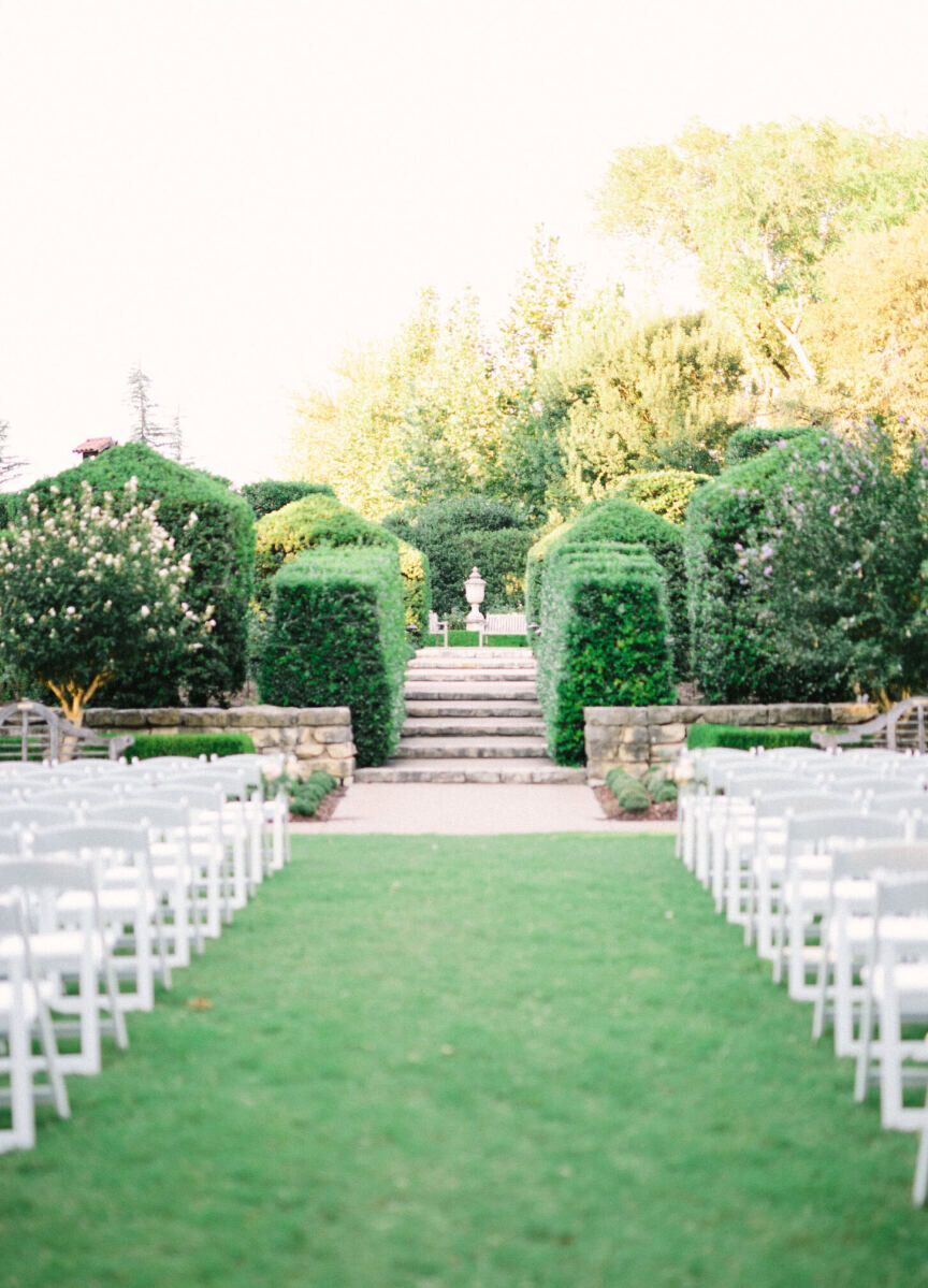 City Weddings: An outdoor ceremony setup at The Dallas Arboretum and Botanical Garden, complete with manicured hedges and white chairs divided to create an aisle.