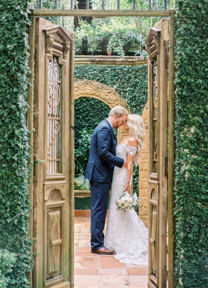 City Weddings: A wedding couple embracing in an indoor-outdoor seeting with a wooden door and hedging in Houston, Texas.