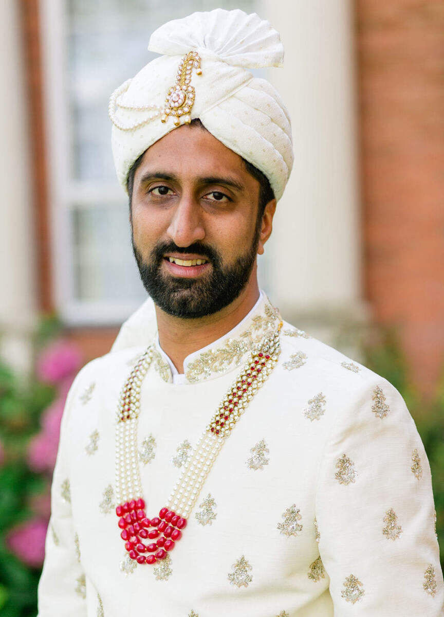 A groom in a Guarav Gupta ensemble pauses for a portrait at his colorful countryside wedding.