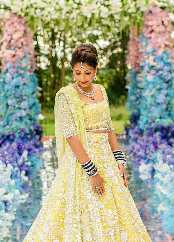 A bride in a yellow lehenga wore her hair in a loose updo at her colorful countryside wedding.