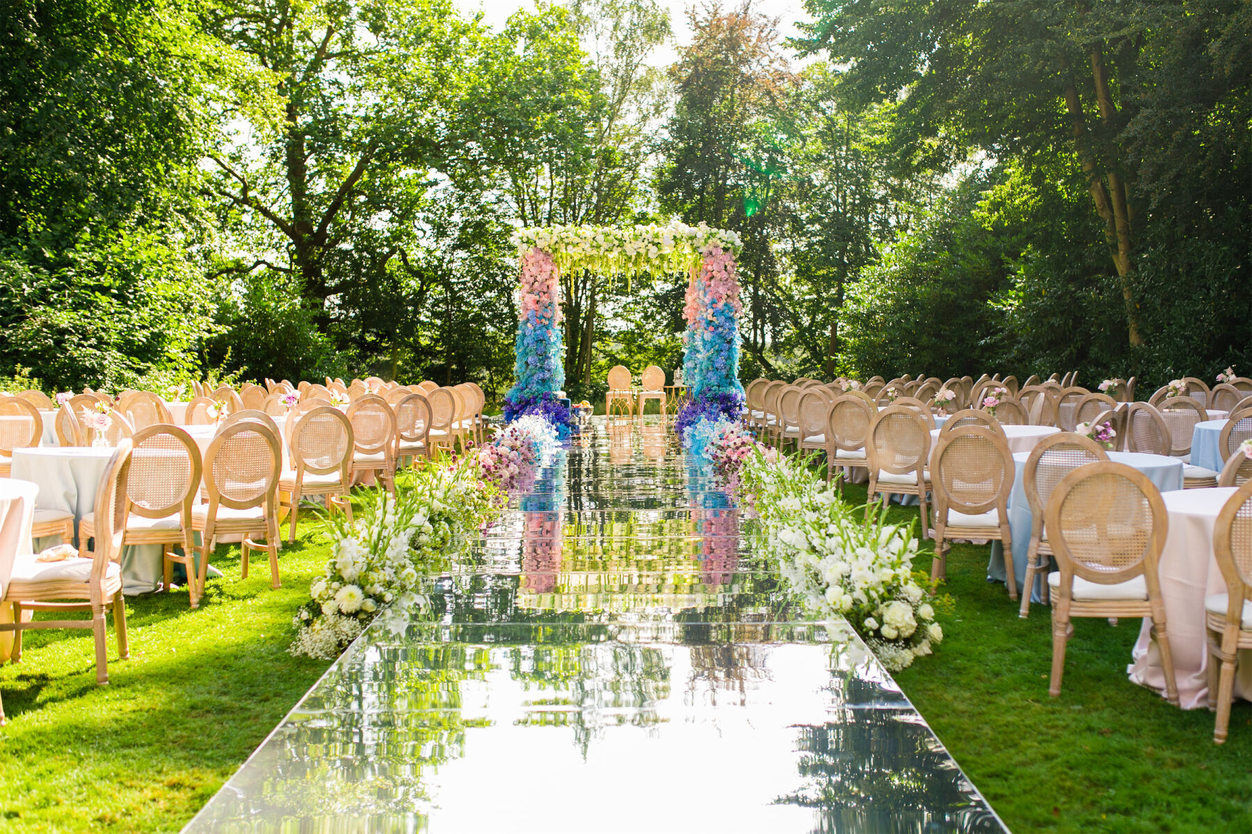 A mirrored aisle led the way to a pink and blue mandap at a colorful countryside wedding in England.
