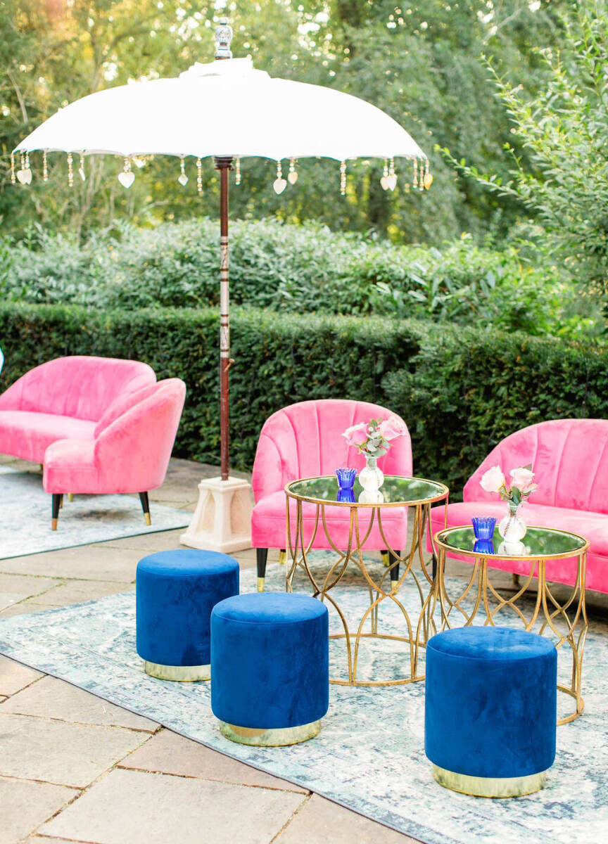 A colorful countryside wedding cocktail hour featured bold lounge furniture and ornate umbrellas and rugs.