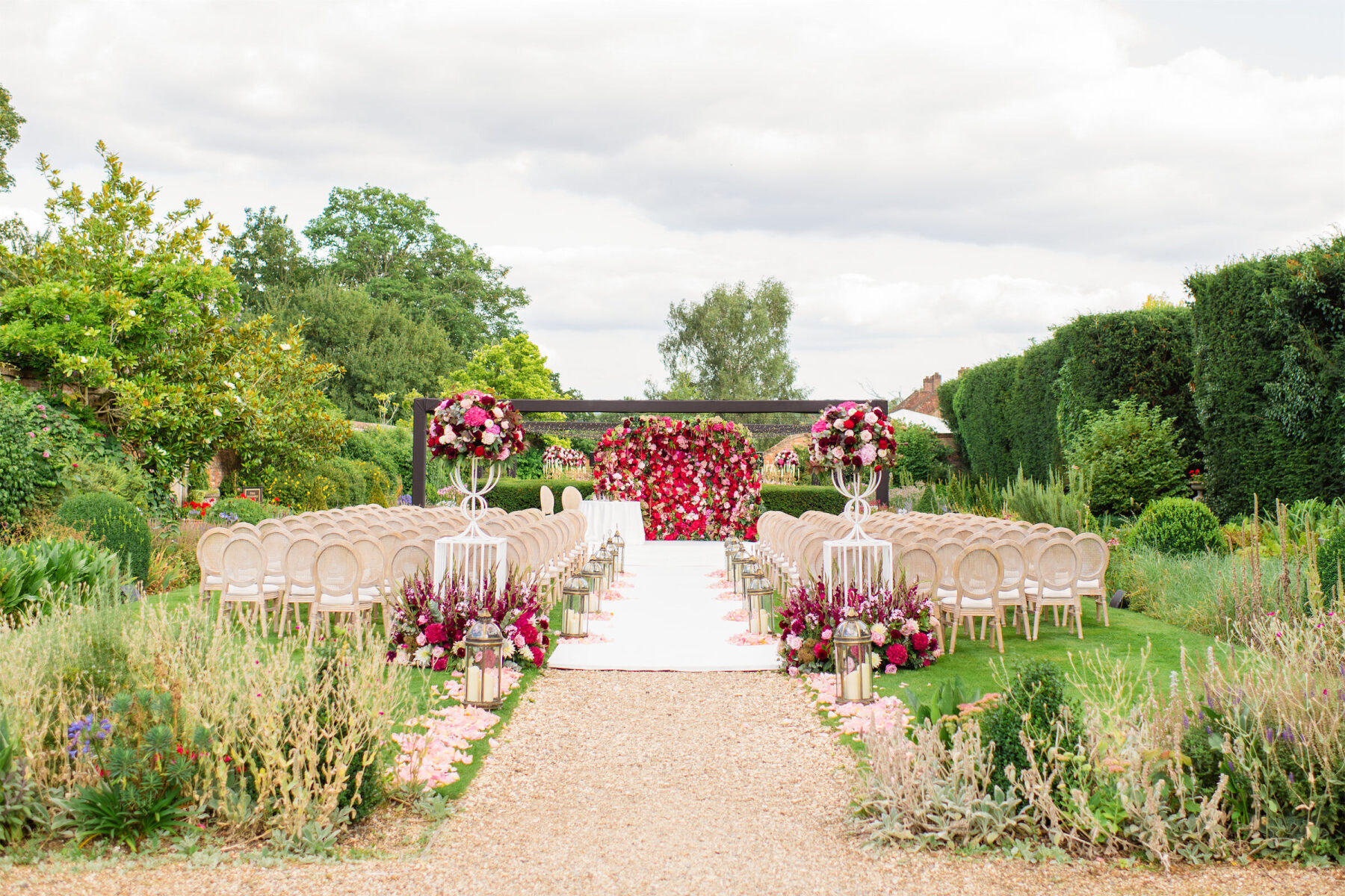 A red and pink floral wall anchored the ceremony space for a colorful countryside wedding.