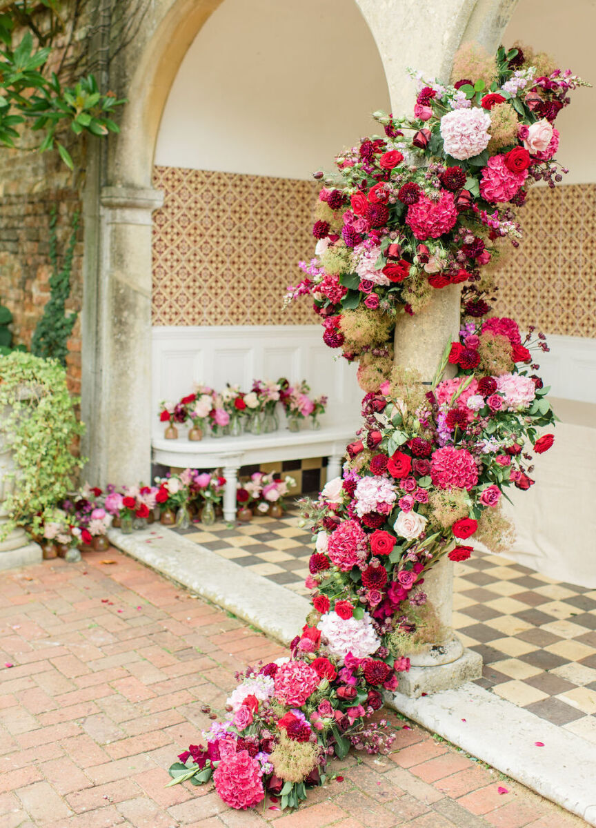 Pink and red flowers wrap around the architecture of the Four Seasons Hotel at a colorful countryside wedding.